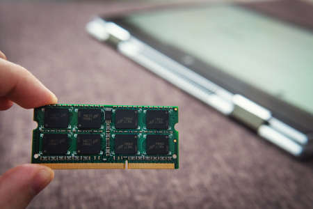 Memory card RAM for laptop on the background of a ultrabook-transformer folded into a tablet. DDR for modern gadgets. Computer repair. Increase the amount of memory for the computer upgrade.の写真素材
