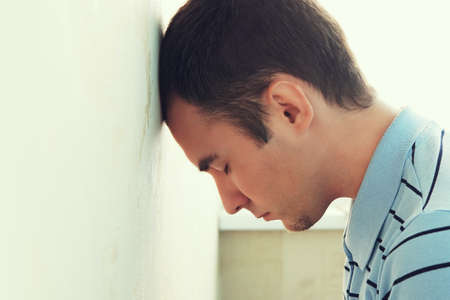 Depressed man his head against a wall. guys banging his head against the wall. Boring guy into depression.の写真素材