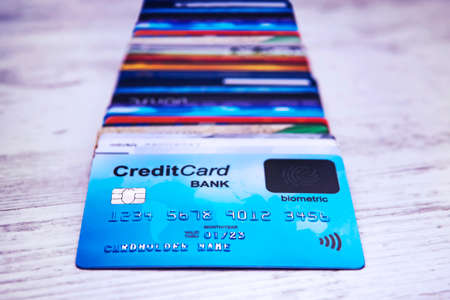 Close up of credit cards stack on wooden surface. Bunch of payment cards with biometric card lying on the top. Concept of paying for purchases using fingerprint scanner. User-friendly technology.の写真素材