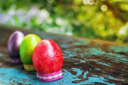 Three colorful easter eggs on blue wooden table. Happy Easter. Village life. Christian tradition....
