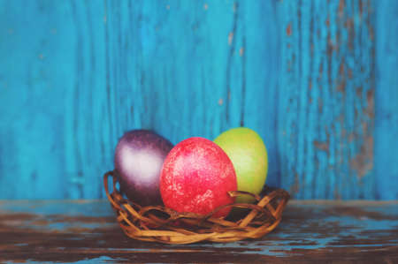 Easter colorful painted eggs in the nest on rustic wooden background. Easter concept. Traditional decorations for the feast of the resurrectionの写真素材
