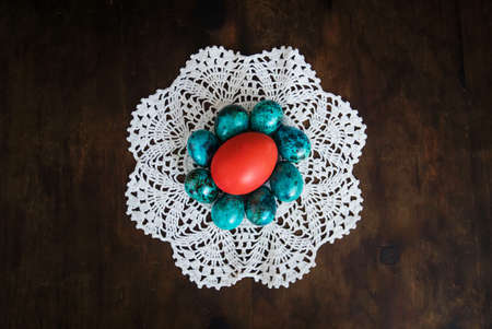 easter eggs on the background of wooden boards. Red chicken egg surrounded by small blue quail eggs on a white tablecloth. Decorations for the celebration of Easter. dark backgroundの写真素材