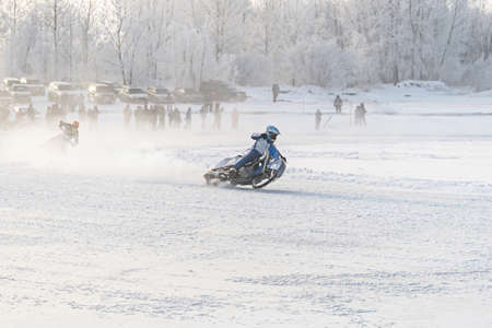 Winter motocross, Driver with motorcycle, race. Winter Speedway. Motorcyclists unmarked go on a winter road entering in dangerous turnの写真素材