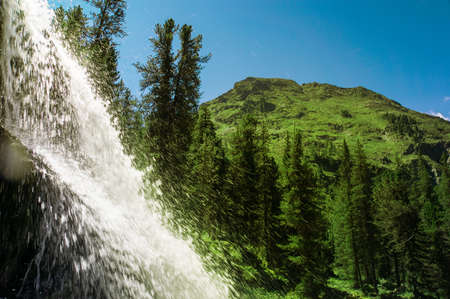 Beautiful torrent of waterfall. Water falling on the falls. On the background of beautiful mountains.の写真素材