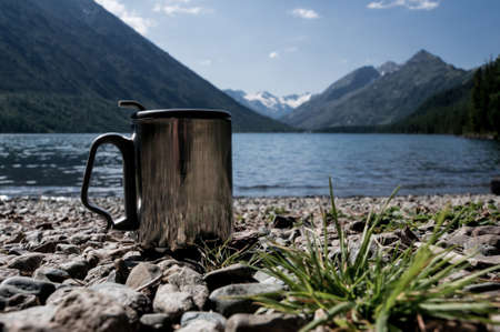 cup of coffee on wood with nature on background. Tourism and travel. Thermal mug for fast boiling waterの写真素材