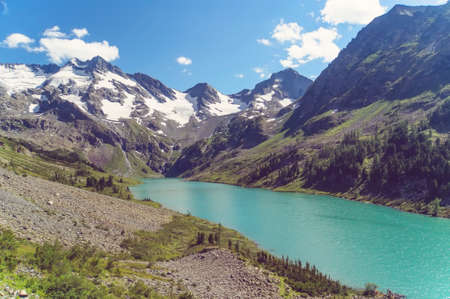 Snow mountains and forests in spring. mountain lake between the mountain slopesの写真素材