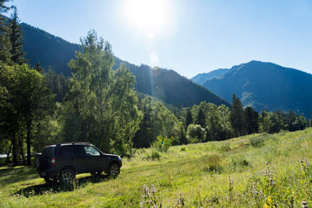 Travel concept with big 4x4 car against sunset and mountains. photo of offroad wheel.の写真素材