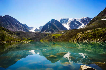 Beautiful mountain lake with turquoise clear water in the Altai Republic Siberia Russia. reflection of mountains with snow-capped peaks in crystal clear water.の写真素材