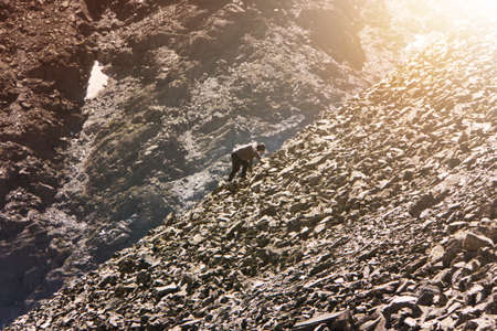 Amateur mountaineering. Man climbing up hill to reach the peak of the mountain. guy climbs up the...
