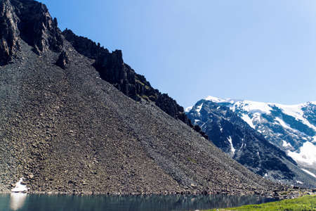 screes. Kurumnik is a pile of fragments of rocks. Scattering of large stones in the Altai mountains on the background of snowy peaks.の写真素材