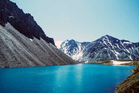 Panorama of the beautiful blue lake in the mountains at evening. bottom of the lake shines well under the rays of the sun. stones in crystal clear water.の写真素材