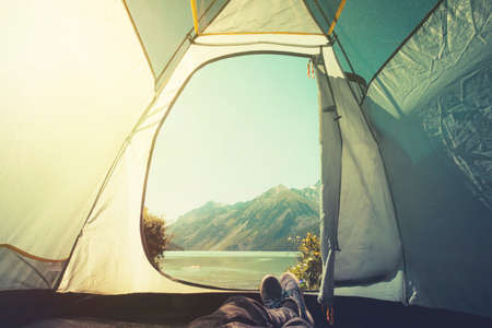 Feet Man relaxing enjoying mountains and lake view from tent camping entrance outdoor Travel Lifestyle concept adventure summer vacations outdoor.の写真素材