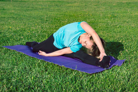 Funny photo about young woman doing yoga exercise with funny grimace. Fitness girl with a smartphone...