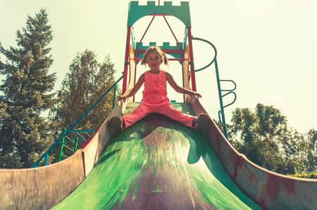 Kids climbing and sliding on outdoor playground. Children play in sunny summer park. Activity and amusement center in kindergarten or school yard. Child on colorful slide. Toddler kid outdoorsの写真素材