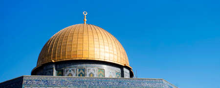 Close up of the Dome of the Rock on the Temple Mount in the Old City of Jerusalem Israel. Golden dome of a temple with walls decorated with mosaic. The upper part of temple with space for your textの写真素材