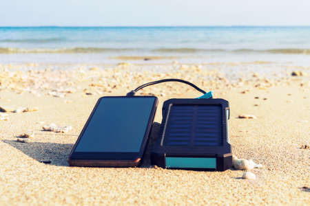Smartphone close up on a sandy beach with copy space, the concept of restoring strength and energy. water protection electronicsの写真素材
