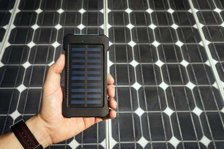 Mobile power Bank to charge your phone and mobile devices on black color solar battery backgroundの写真素材