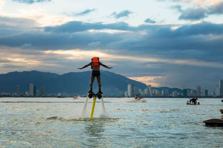 Man posing at new flyboard at tropical beachat sunset. Positive human emotions, feelings, joy. Funny cute men making vacations and enjoying summerの写真素材