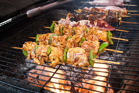 The selective focus pork Barbecue skewers on bamboo sticks . grilling food with vegetables on the stove for barbecue, Thailand Vietnamese or Chinese food. a barbecue in the open air.の写真素材