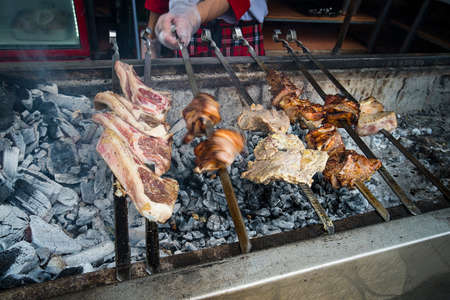 On the barbecue, a lot of meat is roasted on skewers, the chef turns over his shish kebabs. A man's...