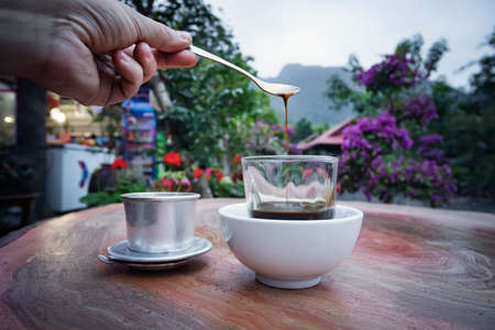 White coffee hot cup morning breakfast on wooden table with blurred mountain background. Selective focus. Breakfast with a Cup of coffee in the beautiful garden in nature.の写真素材