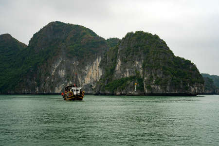 cruising among beautiful limestone rocks and secluded beaches in Ha Long bayの写真素材