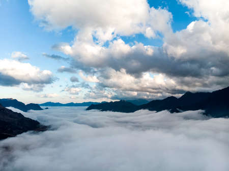 Abstract landscape photograph, mountains shrouded in clouds. Fog floating between mountain peaks, Chinese mountains. Ridgeline artistic landscape image. Clouds settled between mountainsの写真素材