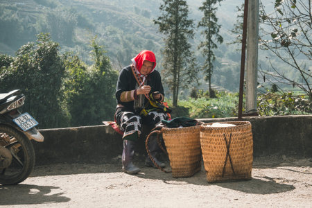Red dzao ethnic minority woman sewing in Sa Pa, Lao Cai province, Vietnam. elderly woman makes souvenirs on the street. TA PHIN, LAO CAI, VIETNAM - 12 January 2019のeditorial素材