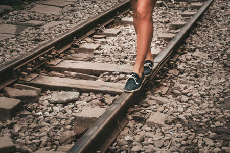 female legs in sneakers on the rail of railwayの写真素材