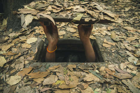 girl going into narrow and small Cu Chi tunnel built by vietnamese guerilla forces during Vietnam war, 60 km from Ho Chi Minh City, Southeast Asiaの写真素材
