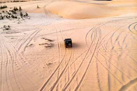 Top view aerial photo from flying drone of a professional driver having dangerous ride with car in desert landscape. Active extreme sport leisure with automobile in arid steppe in sunny day.の写真素材