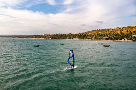 Mui Ne, Vietnam. Man play wind surfing sport in the sea under vast blue skyの写真素材