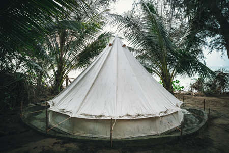 Camping on the white sand beach. tent among palm trees on a tropical island. tent in the form of a...