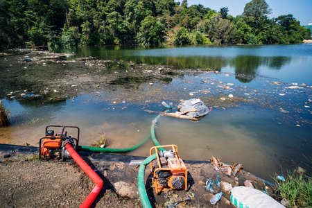 City dump in the pond in the Park. Garbage lies in the water on one of the urban landscape. plastic bottles were thrown into the water. pipes in water.の写真素材