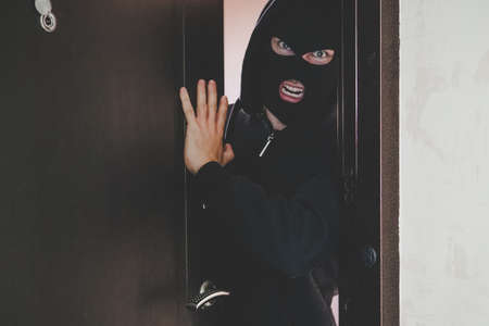 An evil gangster in a black mask covering his face broke the door and broke into the room and...
