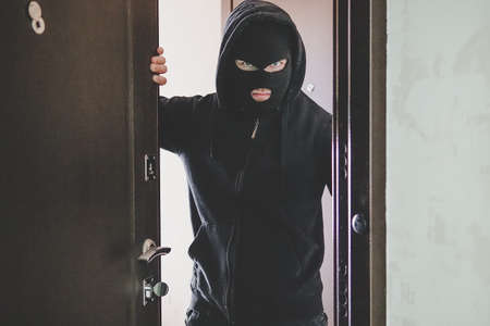 thug keeps the front door Maniac broke into the room. the thief broke down the door. The evil look of the bandit on the camera. dangerous guestの写真素材