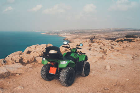 green ATV offroad on sea and sky background. Cyprus Ayia NAPA. quad bike for rent for the entertainment of tourists. Off-road driving in the desertの写真素材