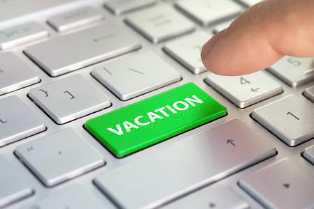 vacation word on computer keyboard button. Finger presses the color button on the gray keyboardの写真素材