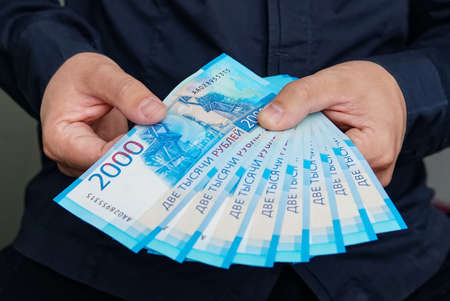 new Russian banknotes denominated in 2000 rubles in male hands close-up on a dark backgroundの写真素材