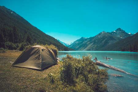 Tourism and traveling concept. Beautiful summer landscape with mountains and tourist tent. Green tent stands near the lake in the mountainsの写真素材