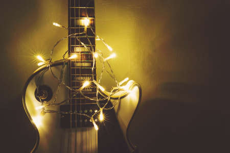 Musical instrument on dark background. Electric guitar with lighted garland on dark background. Gift guitar classic shapes for Christmas or new year.の写真素材