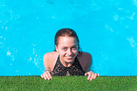 Portrait of trendy fit girl in swim wear with open eyes enjoying rest sunlight over blue water...