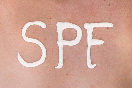 SPF word made of sunblock at woman's back at the beach. Sun protection factor concept. Close-upの写真素材