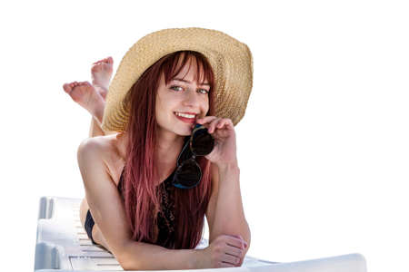 Beautiful girl in beach hat in white lounge isolated on white backgroundの写真素材
