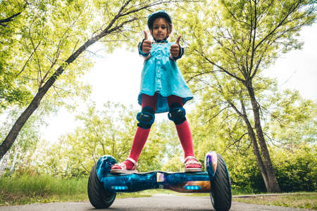 Girl rides on a modern board of self-balancing with a cat in a forest in a summer park. Active lifestyle. Electric scooter. Hover-board. New self-balancing board. Gyro scooterの写真素材