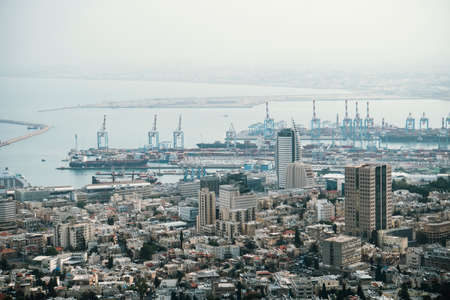 Haifa city landscape. Modern urban buildings in Haifa with many ferry ships, viewing from the air. Aerial view of port of a seaside city shot in early morning. Docks of Haifa, Israel.の写真素材