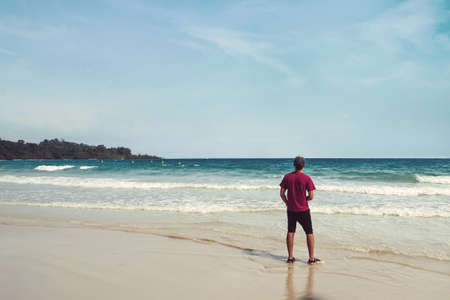 Young man standing on the beach, summer holiday vacationの写真素材