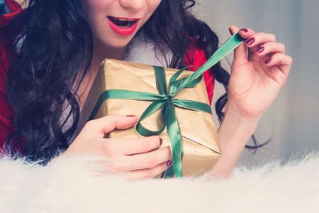 Christmas woman portrait hold christmas gift. Smiling happy girl on Christmas tree background. young woman opens a Christmas gift.の写真素材
