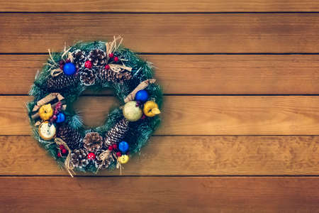 Christmas wreath handmade on a wooden background. Festive lights of garland. New Years interior decoration. copy space for text.の写真素材