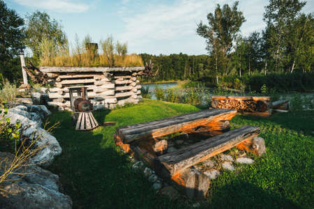 Small log houses for outdoor recreation are located on the river Bank. Hunting ground. Tourist base. Table of logs in the camping for tourists. Home and garden furniture. agrotourismの写真素材